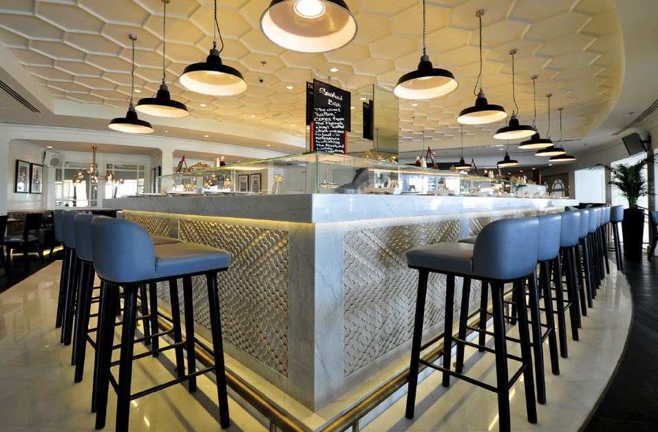 bar design featuring bar chairs with blue lether and black industrial pending lamps by bond interiors